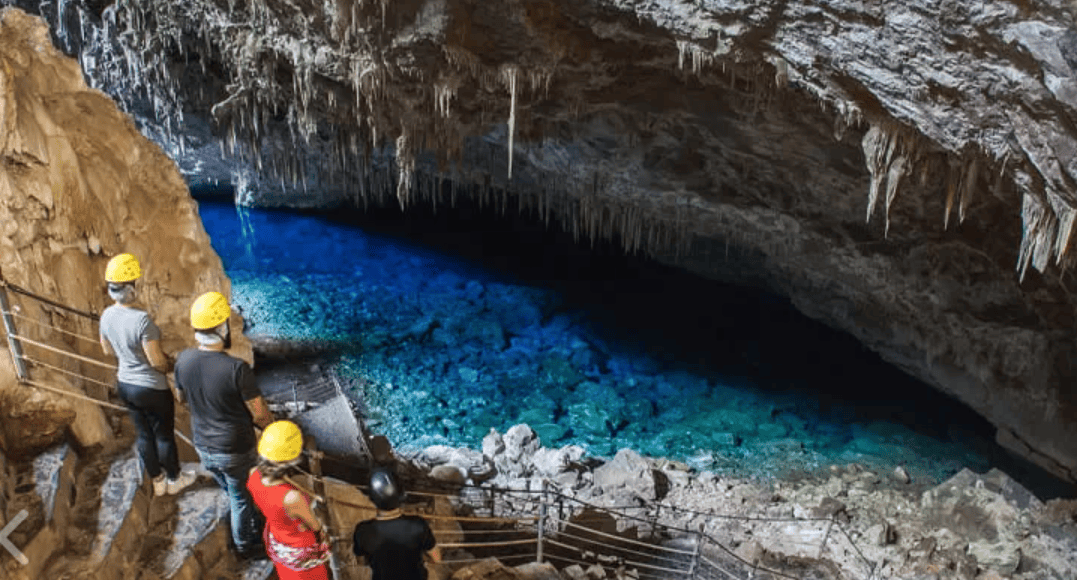 Grupo de visitantes com capacetes observando o Lago Azul dentro da Gruta do Lago Azul em Bonito MS